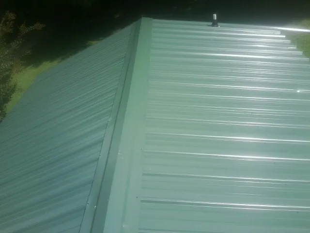 New green metal panels meeting at the ridge of a roof — Flat Roof Repair work by our crew in Erwin